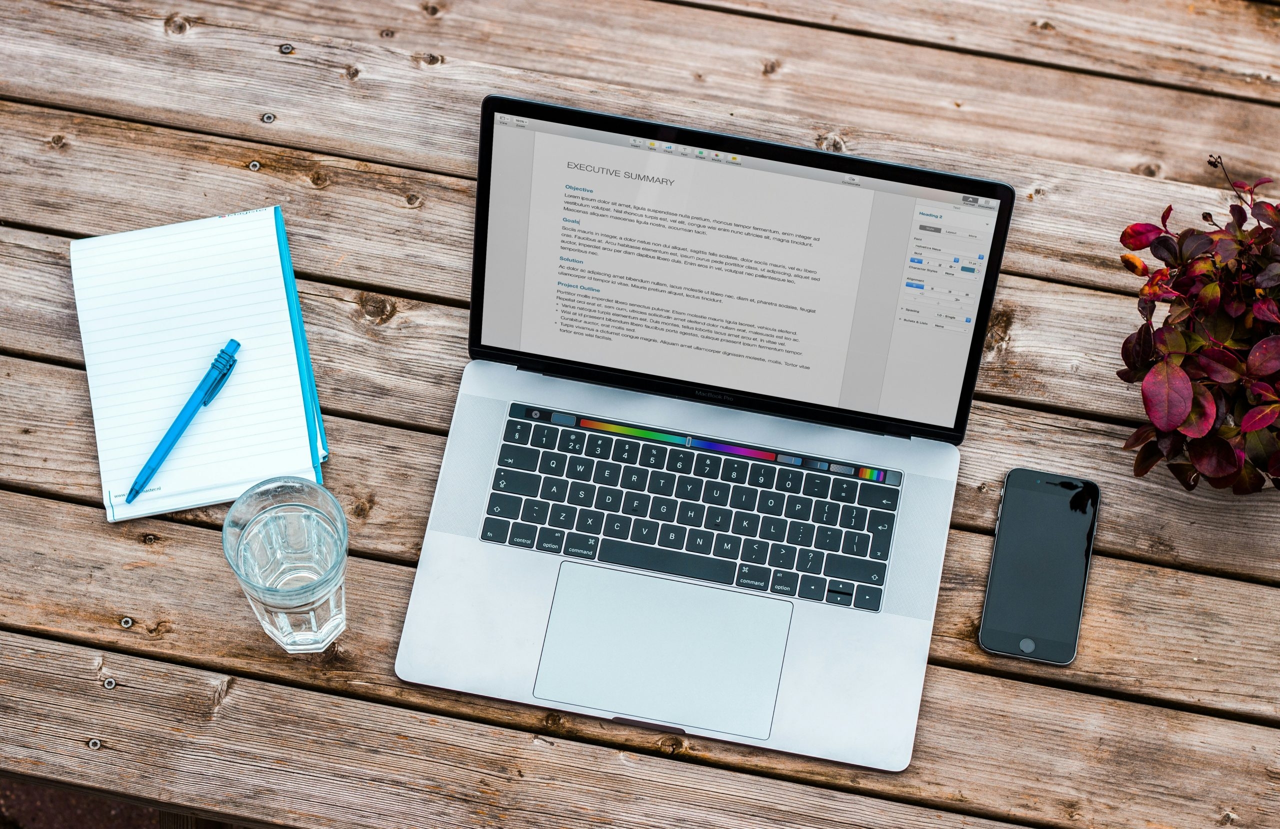 Laptop, phone and notepad on a desk outside