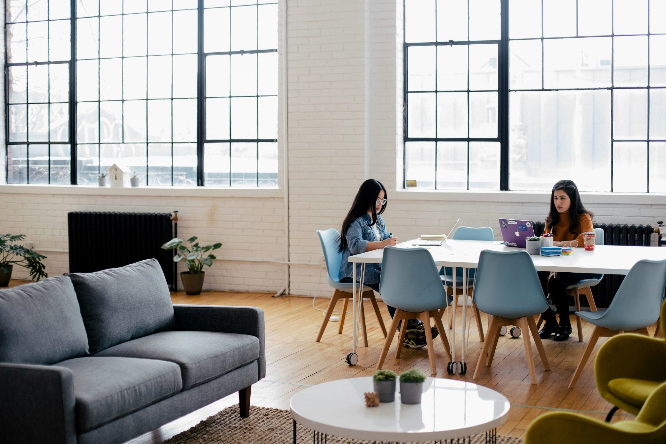 people sat at a desk working with big windows behind them